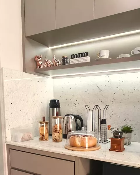 A área de café: as xícaras da Dent Art na prateleira iluminada, potes de biscoito e o pão