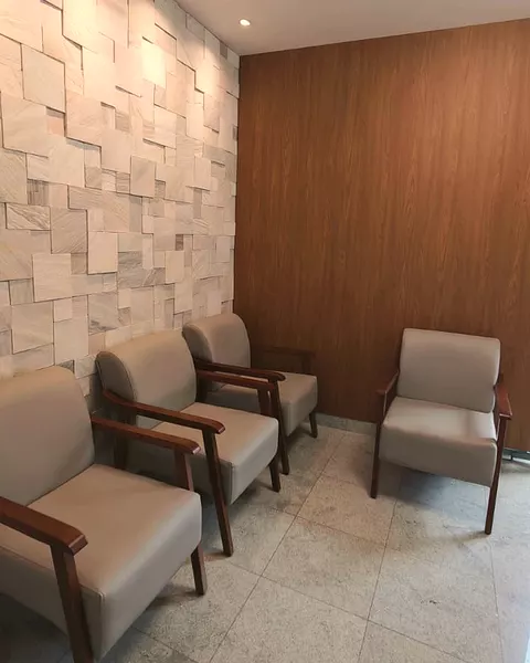 A parede de pedra e o painel de madeira da sala de espera, com as poltronas